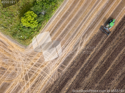 Image of An agricultural field after harvesting with tractor plowing the soil on a summer day. Top view