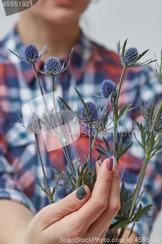 Image of woman holding blue flowers eryngium