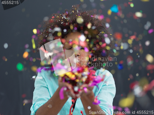 Image of black woman blowing confetti in the air