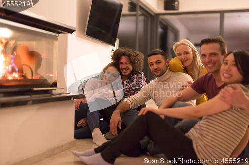 Image of multiethnic couples sitting in front of fireplace