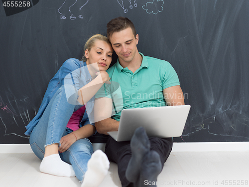 Image of couple using laptop in front of gray chalkboard