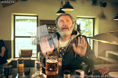 Image of The senior bearded male drinking beer in pub