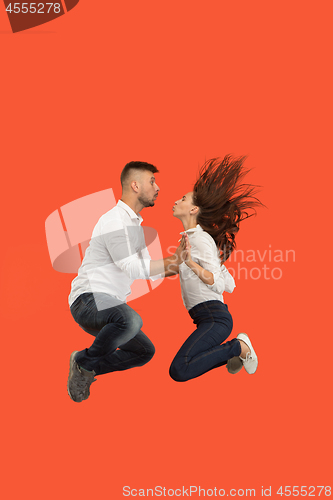 Image of Freedom in moving. Pretty young couple jumping against red background