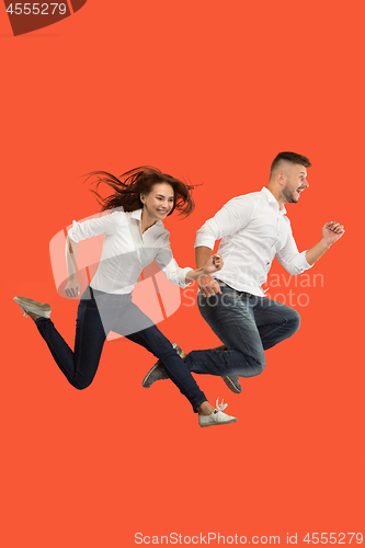 Image of Freedom in moving. Pretty young couple jumping against red background