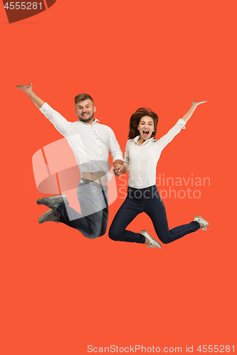 Image of Freedom in moving. Pretty young couple jumping against red background