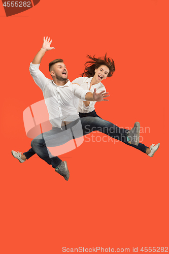 Image of Freedom in moving. Pretty young couple jumping against red background