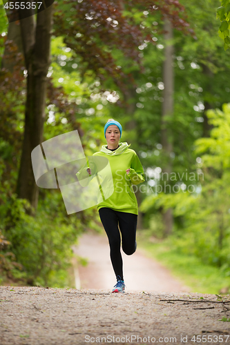 Image of Sporty young female runner in the forest.