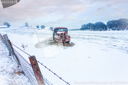 Image of Rusty old car sits in a snow covered rural field
