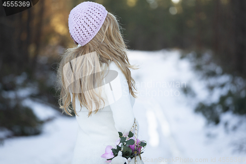 Image of Woman standing on a snow covered road in forest