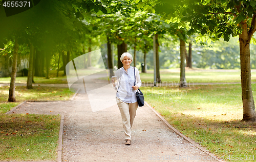 Image of senior woman walking with takeaway coffee at park