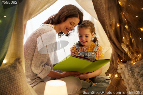 Image of happy family reading book in kids tent at home