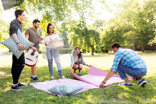 Image of friends arranging place for picnic at summer park