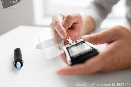 Image of senior man with glucometer checking blood sugar