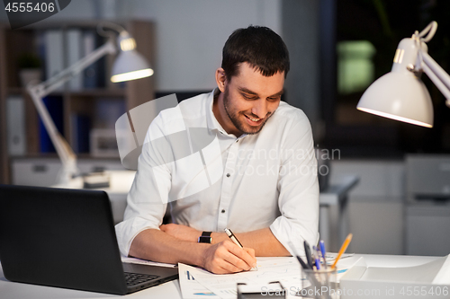 Image of businessman with papers working at night office