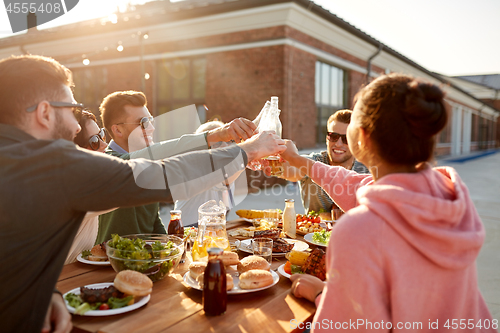 Image of happy friends toasting drinks at rooftop party