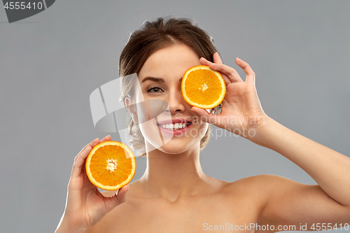 Image of smiling woman with oranges over grey background