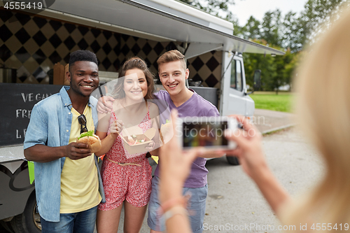 Image of woman photographing friends eating at food truck