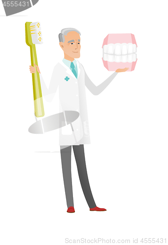 Image of Dentist with dental jaw model and toothbrush.