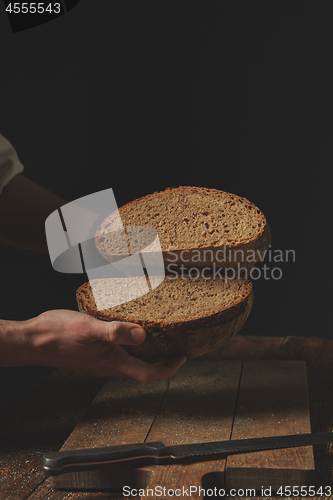 Image of man baker holds in his hands halves of rye bread,