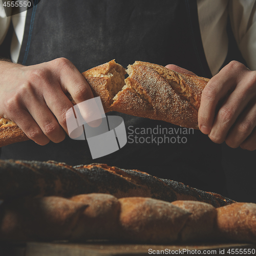 Image of organic delicious baguette halves in the hands of man