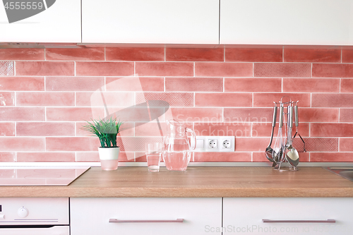 Image of Modern kitchen at home with kitchenware and flowerpot on a top and wall tiles in a trend color of the year 2019 Living Coral Pantone.