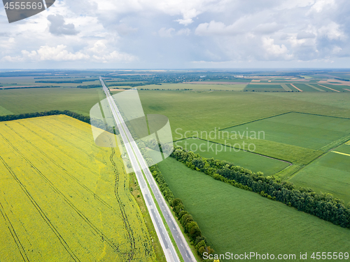 Image of Panoramic aerial view from drone of a highway with cars on it, fields, tree planting at summer sunset.