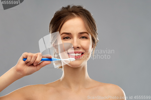 Image of smiling woman with toothbrush cleaning teeth