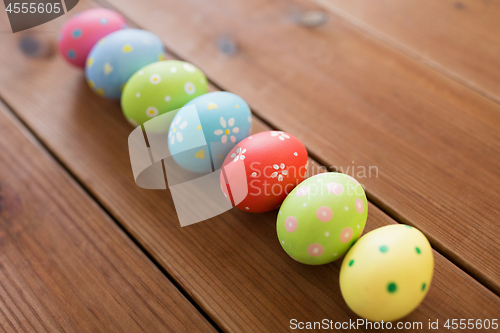 Image of row of colored easter eggs on wooden table