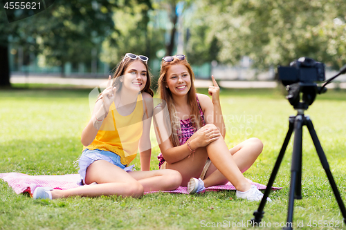 Image of teenage bloggers recording video by camera in park