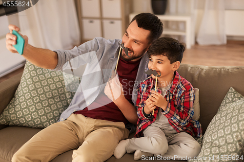 Image of father and son taking selfie at home