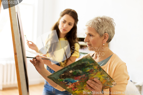 Image of senior woman painting at art school studio