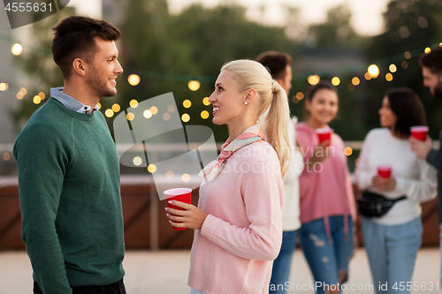 Image of friends with drinks in party cups at rooftop