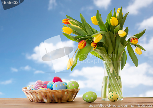 Image of colored easter eggs in basket and flowers