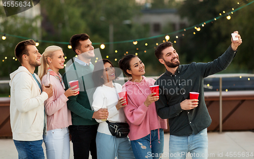 Image of friends with drinks taking selfie at rooftop party