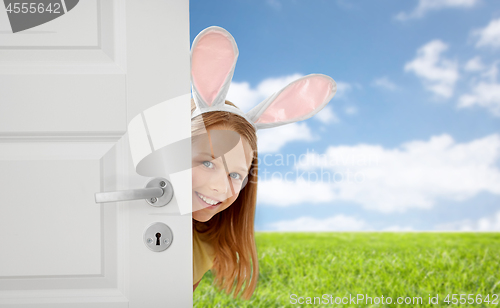 Image of happy girl with easter bunny ears peeking out door