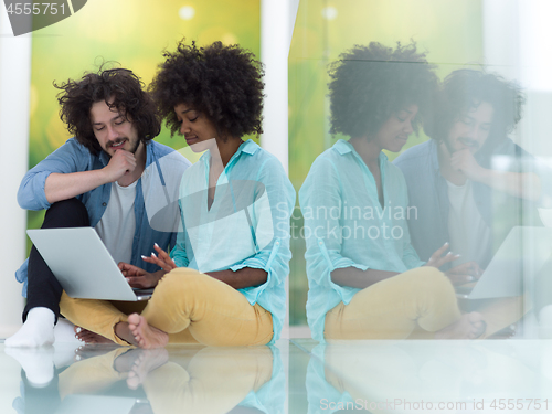 Image of multiethnic couple using a laptop on the floor