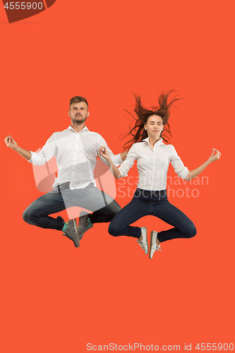 Image of Freedom in moving. Pretty young couple jumping against red background