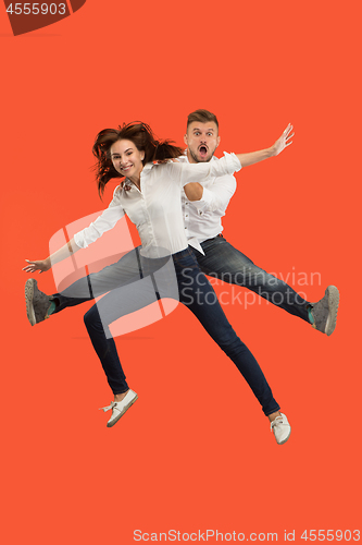 Image of Freedom in moving. Pretty young couple jumping against red background