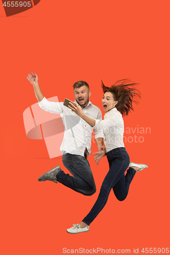 Image of Full length of young couple with mobile phone while jumping