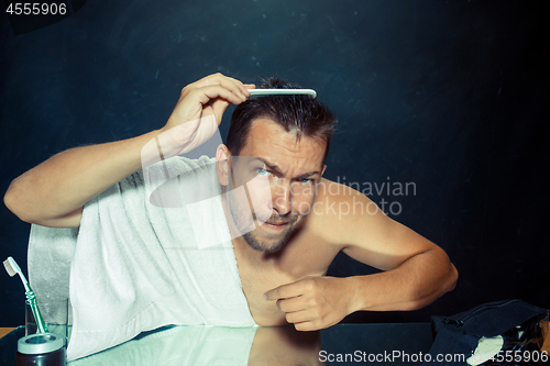 Image of Man With Comb Concerned About Hair Loss