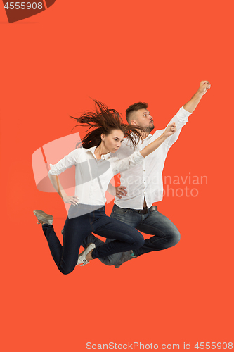 Image of Freedom in moving. Pretty young couple jumping against red background