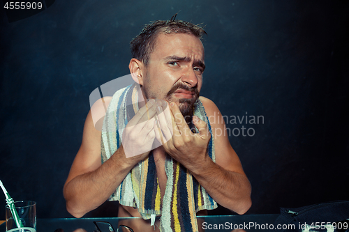 Image of Close up photo of young man looking for acnes on his face