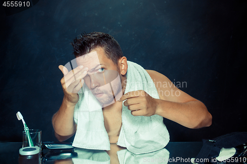 Image of Close up photo of young man looking for acnes on his face