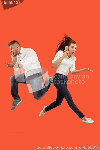 Image of Full length of young couple with mobile phone while jumping