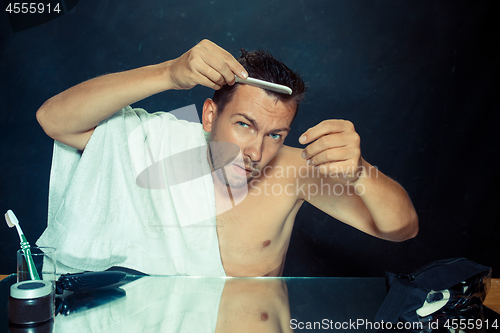 Image of Man With Comb Concerned About Hair Loss