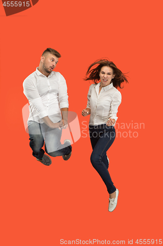 Image of Freedom in moving. young couple jumping against red background