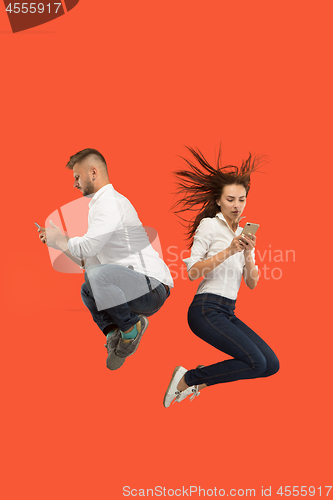 Image of Full length of young couple with mobile phone while jumping