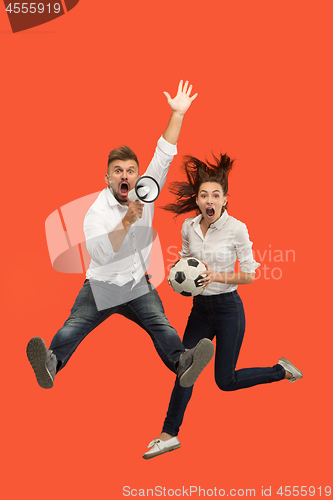 Image of The young man and woman as soccer football players kicking the ball at studio