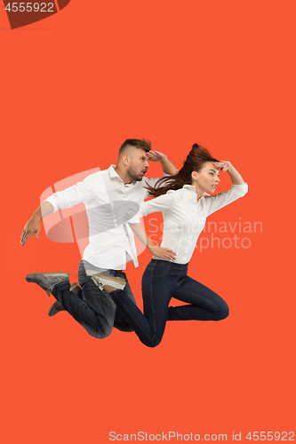 Image of Freedom in moving. Pretty young couple jumping against red background