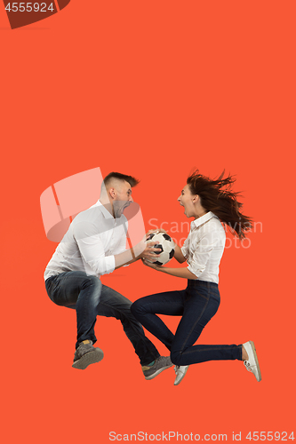 Image of The young man and woman as soccer football players kicking the ball at studio